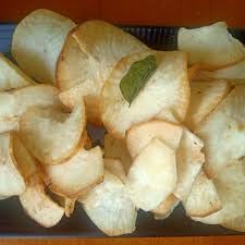 Professional overhead shot of Paithrka Tapioca Chips, featuring a black bowl filled with crispy, ridged golden-brown cassava chips and a branded product pouch on a white marble background